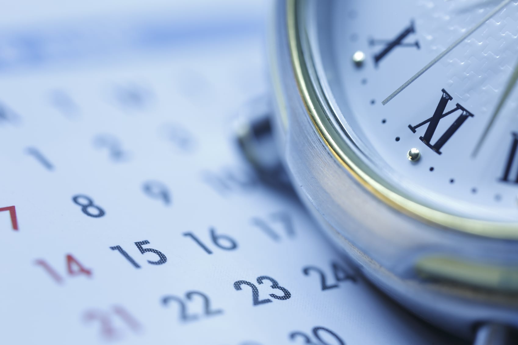 Close-up of a calendar page displaying numbers alongside a partial view of a pocket watch, symbolizing time and planning. Much like custom tents tailored to your needs, the focus is on the intersection of dates and time for personalized organization.