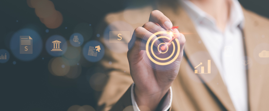 A person in a beige jacket is drawing a glowing target symbol on a transparent screen with a light pen. Various icons, such as paper, building, and graph—much like blueprints for custom pop up tents—suggest concepts like planning and analysis. The background is softly blurred.