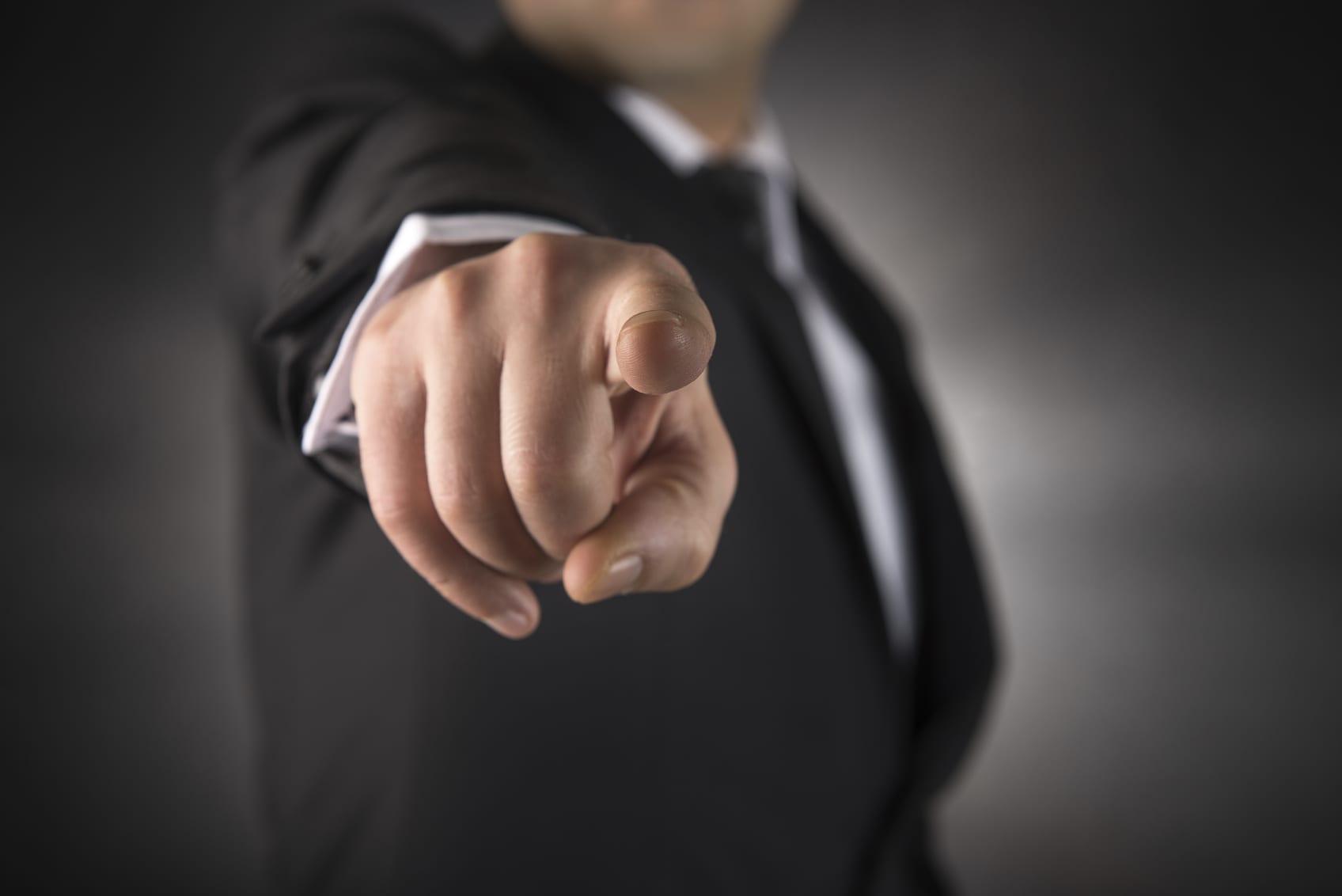 A person in a suit is pointing directly at the camera, their finger sharply in focus against a blurred backdrop—much like the immediacy of assembling pop-up tents, capturing urgency and emphasis.
