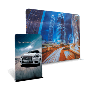 A Lexus trade show booth showcases two panels: one with a car driving on a road at dusk, highlighting the brand's logo, and another with a cityscape of skyscrapers illuminated at night.