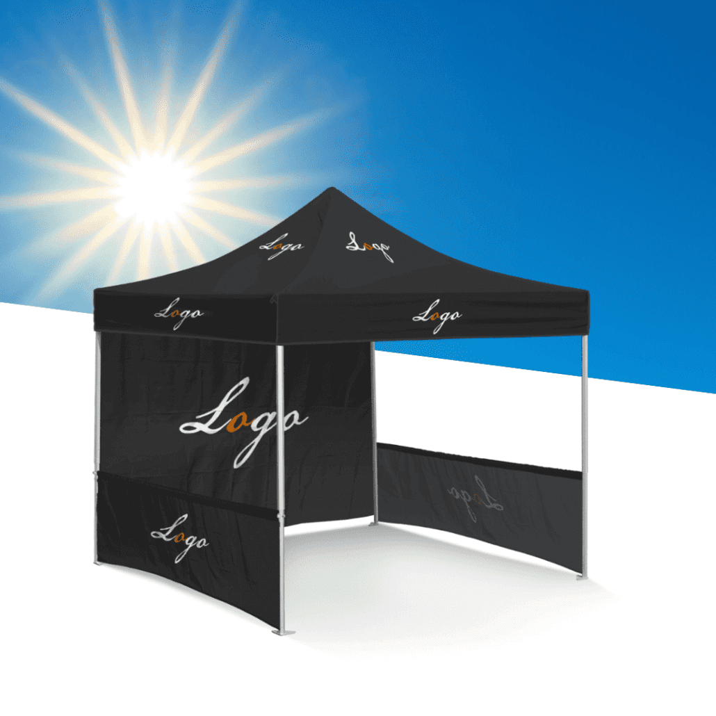 A black canopy tent with a Soccer Tents logo printed on the fabric stands under a bright, sunny sky. The tent features a sloped roof and side walls, set against a white surface with a clear blue sky in the background.