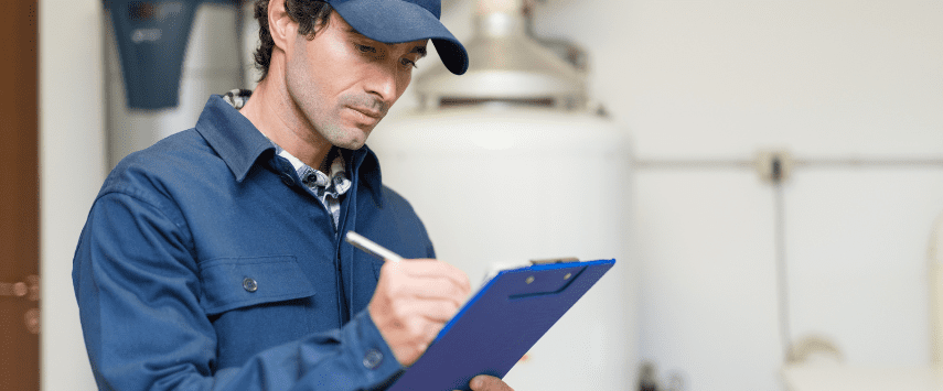 A man in a blue uniform and cap is meticulously writing on a blue clipboard, appearing to manage the setup of an inflatable event. His focus is unwavering, ensuring every detail in the utility room aligns perfectly with the service's standards.