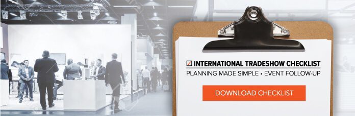 A clipboard with International Tradeshow Checklist: Planning Made Simple - Event Follow-Up written on paper. A red button says Download Checklist. In the background, people are walking through a tradeshow with booths and displays.