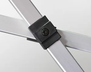 Close-up of a metal easel joint on a 10 x 10 canopy, featuring two intersecting silver aluminum bars connected by a black plastic bracket with a centered screw. The background is plain and light-colored.