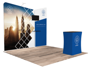Explore the 10'x10' Quick-N-Fit Booth - Package #1104, featuring a city skyline backdrop interwoven with geometric patterns. This trade show display comes equipped with a monitor, branded graphics showcasing your logo, and a compact counter on a wooden floor.