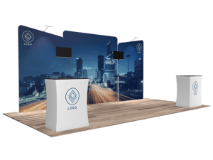 The 10'x20' Quick-N-Fit Booth - Package # 1204 includes a cityscape backdrop, two large digital screens, and a counter. The geometric logo is prominently displayed on both the backdrop and the counter, with wooden flooring adding a polished finish to the setup.
