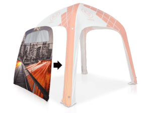 An orange and white inflatable canopy with a geometric pattern and a logo. A side panel with a cityscape print is shown detached, indicated by an arrow.