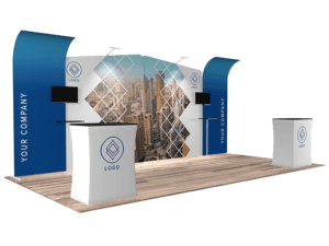 A 10'x20' Quick-N-Fit Booth - Package # 1214 features two curved blue panels showcasing "Your Company" and a central cityscape mural. At each end, two podiums bearing logos are set on a wooden floor, illuminated by overhead lighting fixtures.