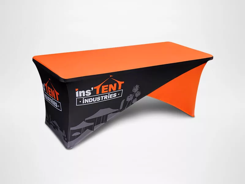 A rectangular table features a vibrant orange and black fitted cover. The cover displays the logo and name ins TEN T INDUSTRIES in bold letters on the side. The table is set against a plain white background.