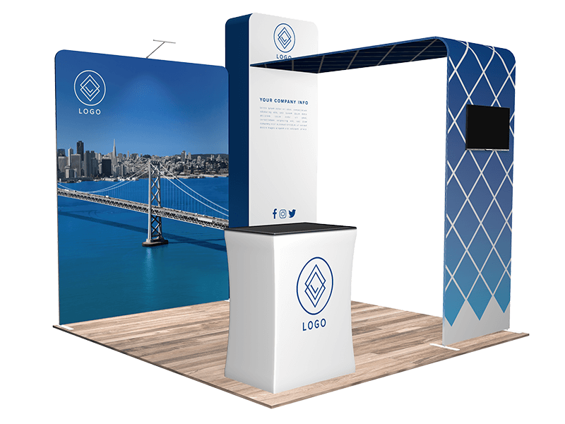 A trade show booth display featuring a large backdrop with a city skyline and bridge. The setup includes a curved reception counter and an arch with a grid pattern and a screen. Logos are visible on the counter, backdrop, and arch.