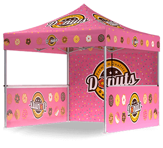 A pink pop-up canopy tent decorated with images of donuts and the word Donuts in large letters. The tent features donut graphics on the roof, sides, and back wall.
