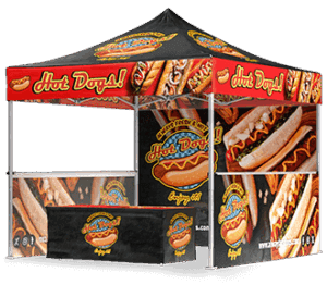 A colorful outdoor booth with a canopy and banners decorated with images of hot dogs and the words Hot Dogs! in bold, red letters, promoting a hot dog stand or vendor.