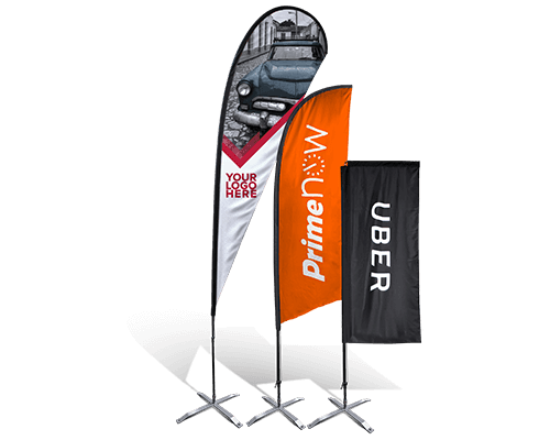 Three vertical promotional flags on metal stands. The first has a car image and Your Logo Here, the second is orange with PrimeNow, and the third is black with UBER in white text.