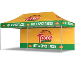 A yellow and green pop-up canopy tent with HOT & SPICY TACOS and taco graphics along the edges. The front and roof display the word Tacos in bold red letters on a yellow background.