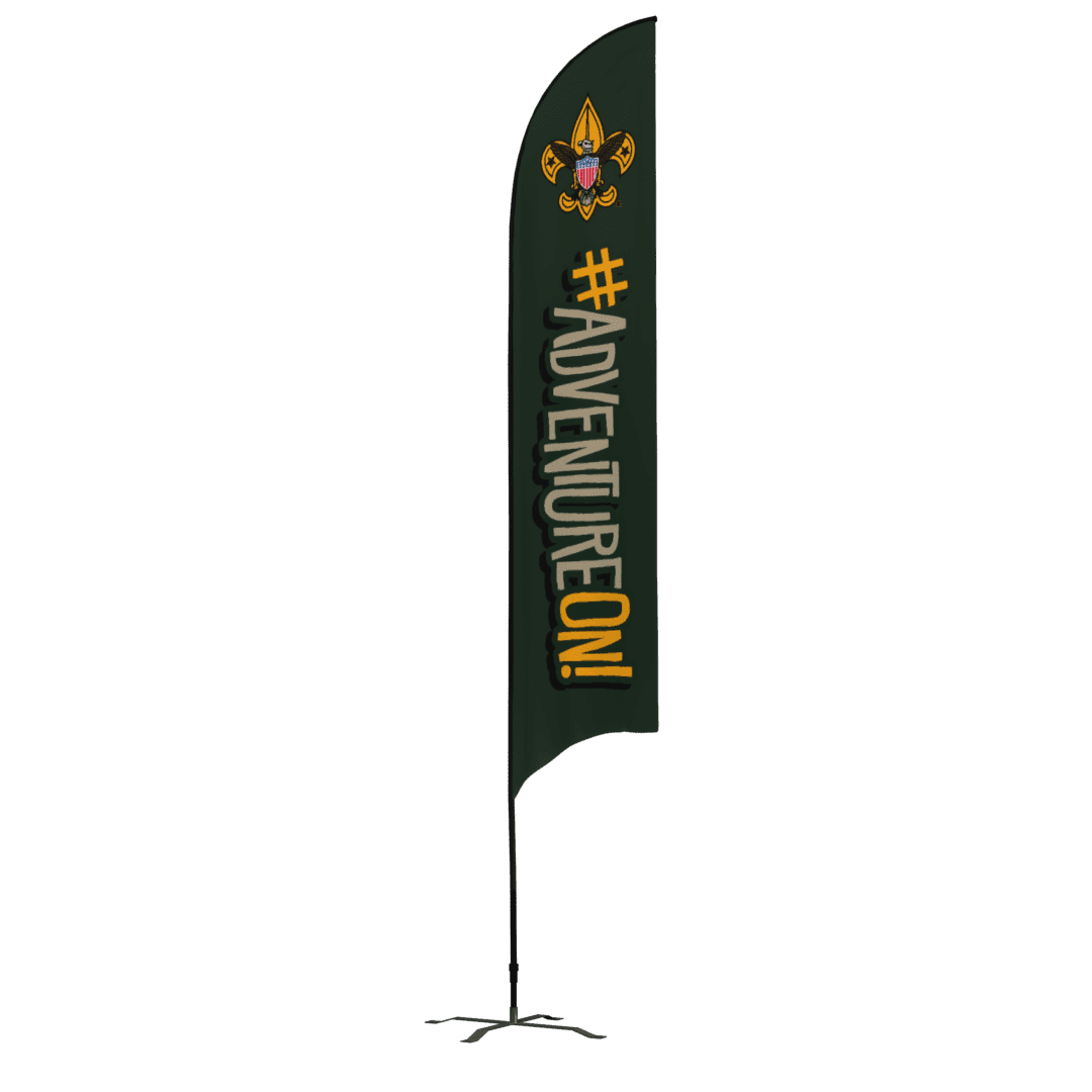 A tall green flag with the Boy Scouts emblem at the top and the words #ADVENTUREON! in bold yellow and white letters, standing on a black pole with a cross-shaped base.