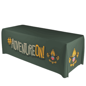 A dark green tablecloth with #ADVENTUREON! written in large letters and two Boy Scouts of America emblems on the front corners.