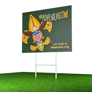 A billboard with the Boy Scouts of America logo, the words #ADVENTUREON!, and the text Join today at beascout.org stands on a patch of green grass.