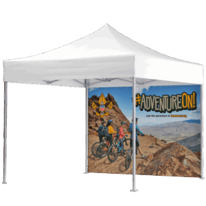 A white pop-up canopy tent with a back panel displaying four people with bikes on a rocky mountain trail, mountains in the background, and #ADVENTUREON! with a Boy Scouts logo and website text.