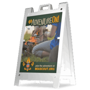 A sign with the message #ADVENTUREON! shows kids roasting marshmallows over a campfire. The bottom reads, Join the adventure at BEASCOUT.ORG with the Boy Scouts of America logo.