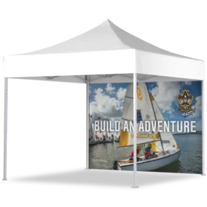 A white outdoor canopy tent with a printed backdrop showing sailboats on water and the words Build an Adventure along with the Scouts BSA logo and website.