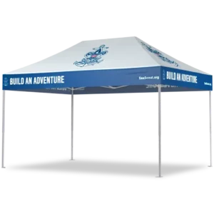 A white canopy tent with blue trim displaying the text BUILD AN ADVENTURE and an anchor logo. The tent is supported by four metal legs and has SeaScout.org written on one side.
