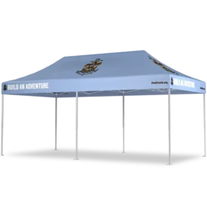 A light blue outdoor canopy tent with BUILD AN ADVENTURE printed on the valance and a sailing ship logo on the roof, supported by four metal legs.