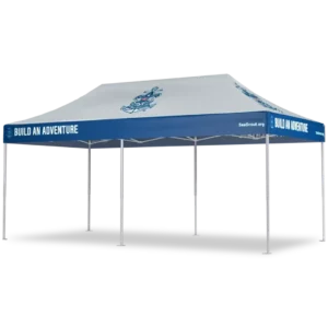 A large outdoor canopy tent with a white roof featuring a blue maritime logo and blue trim that reads BUILD AN ADVENTURE along the edges. The tent is supported by multiple white poles.