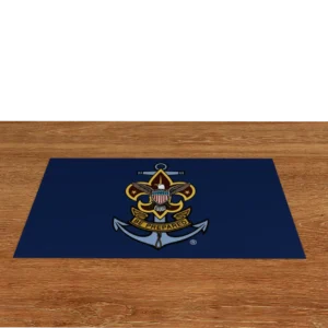 A blue mat with a Boy Scouts of America emblem featuring an anchor, eagle, shield, stars, and the motto Be Prepared, placed on a wooden floor with a black background.