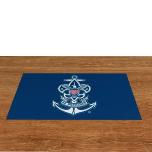 A blue mat with a white anchor, fleur-de-lis, and shield emblem in the center, featuring a banner that reads Be Prepared, placed on a wooden surface.