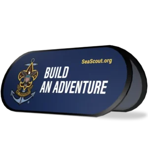 A navy blue sign with the Sea Scouts anchor emblem, the words BUILD AN ADVENTURE, and the website SeaScout.org in yellow text.