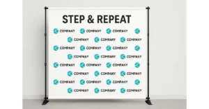 A white step and repeat banner with the words STEP & REPEAT at the top and rows of teal circular logos and the word COMPANY printed repeatedly across the backdrop. The banner is supported by a black metal frame.