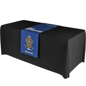 A black table covered with a blue runner featuring the Sea Scouts logo—a fleur-de-lis, ship’s wheel, and anchor—and the text “SeaScout.org.”.