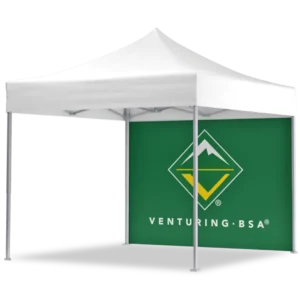 A white canopy tent with a green back wall featuring the Venturing BSA logo, which consists of a yellow diamond and a white mountain graphic, and the text VENTURING BSA in white.
