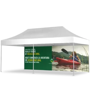 A white outdoor canopy tent with a printed side panel showing a person kayaking on a river and a bilingual message promoting beascout.org and seunscout.org in English and Spanish.