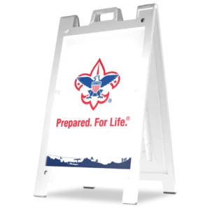 A white A-frame sign displays the Boy Scouts of America logo above the words “Prepared. For Life.®” in red, with a blue silhouette of outdoor activities at the bottom.