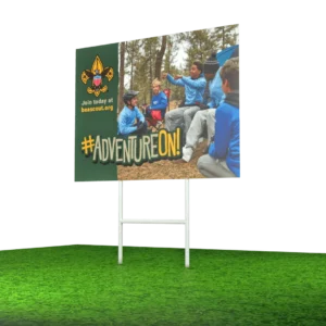 A billboard on grass shows children in scout uniforms sitting outdoors. Text reads “#ADVENTUREON!” and “Join today at beascout.org” with a scouting logo in the top left corner.