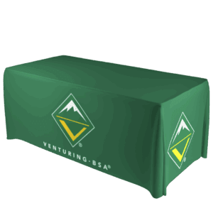 A green tablecloth with the Venturing, BSA logo, which features a stylized mountain inside a diamond shape, draped over a rectangular table. The logo and Venturing, BSA text appear on the front and side.