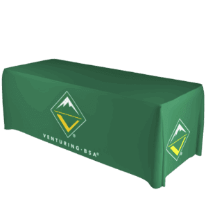 A green tablecloth covers a rectangular table, featuring the Venturing BSA logo with a mountain and a yellow V inside a green diamond, along with the text VENTURING BSA printed on the front.