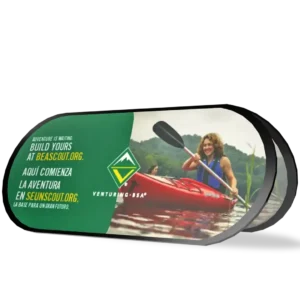 A smiling person paddles a red kayak on a lake. Next to them, text in English and Spanish promotes Venturing BSA and encourages visiting beascout.org and seunscout.org to start an adventure.