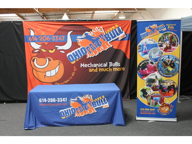 A 10x8 printed tradeshow backdrop for Ohio Party Bull, featuring a cartoon bull logo, contact details, Mechanical Bulls and much more slogan, and photos of people on mechanical bulls and inflatables.