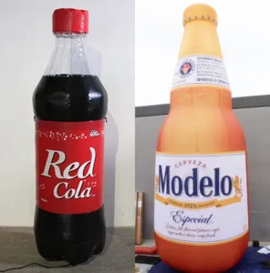 Two large bottles side by side: one is a red-labeled Red Cola soda bottle, and the other is an oversized beer bottle with a tan label reading Modelo Especial. Both bottles are standing on flat surfaces.