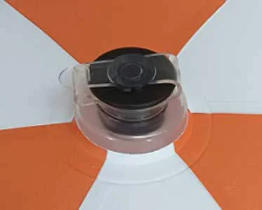 Close-up of an air valve on an inflatable orange and white beach ball, showing the transparent plastic seal over the black valve.