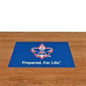 A blue mat on a wooden floor features the Boy Scouts of America emblem and the slogan Prepared. For Life. in white text.