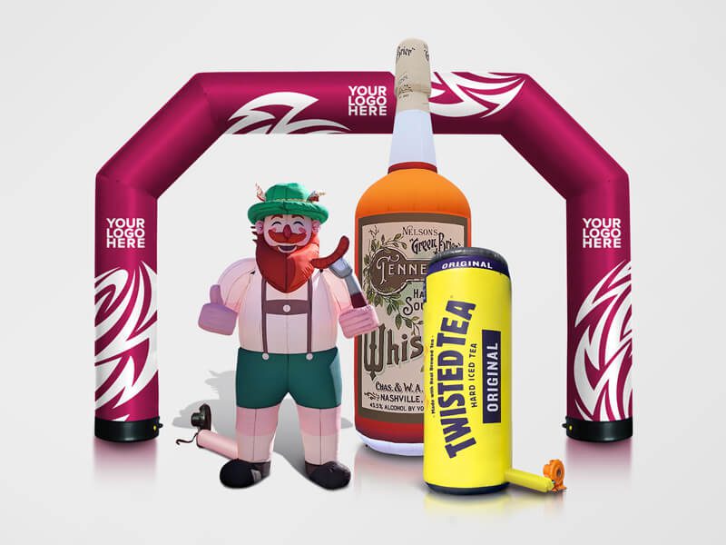 A group of large inflatable props, including a whiskey bottle, a can of Twisted Tea, a cartoonish character in lederhosen, and a magenta archway with “Your Logo Here” text in white—perfect alongside custom tents for standout event branding.