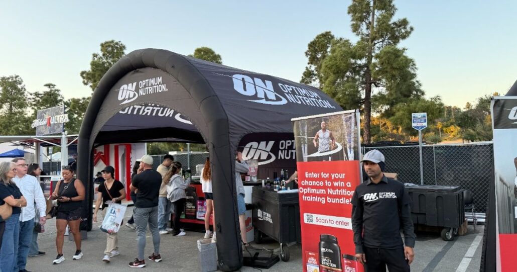 A branded Optimum Nutrition inflatable booth setup with banners and product displays outdoors